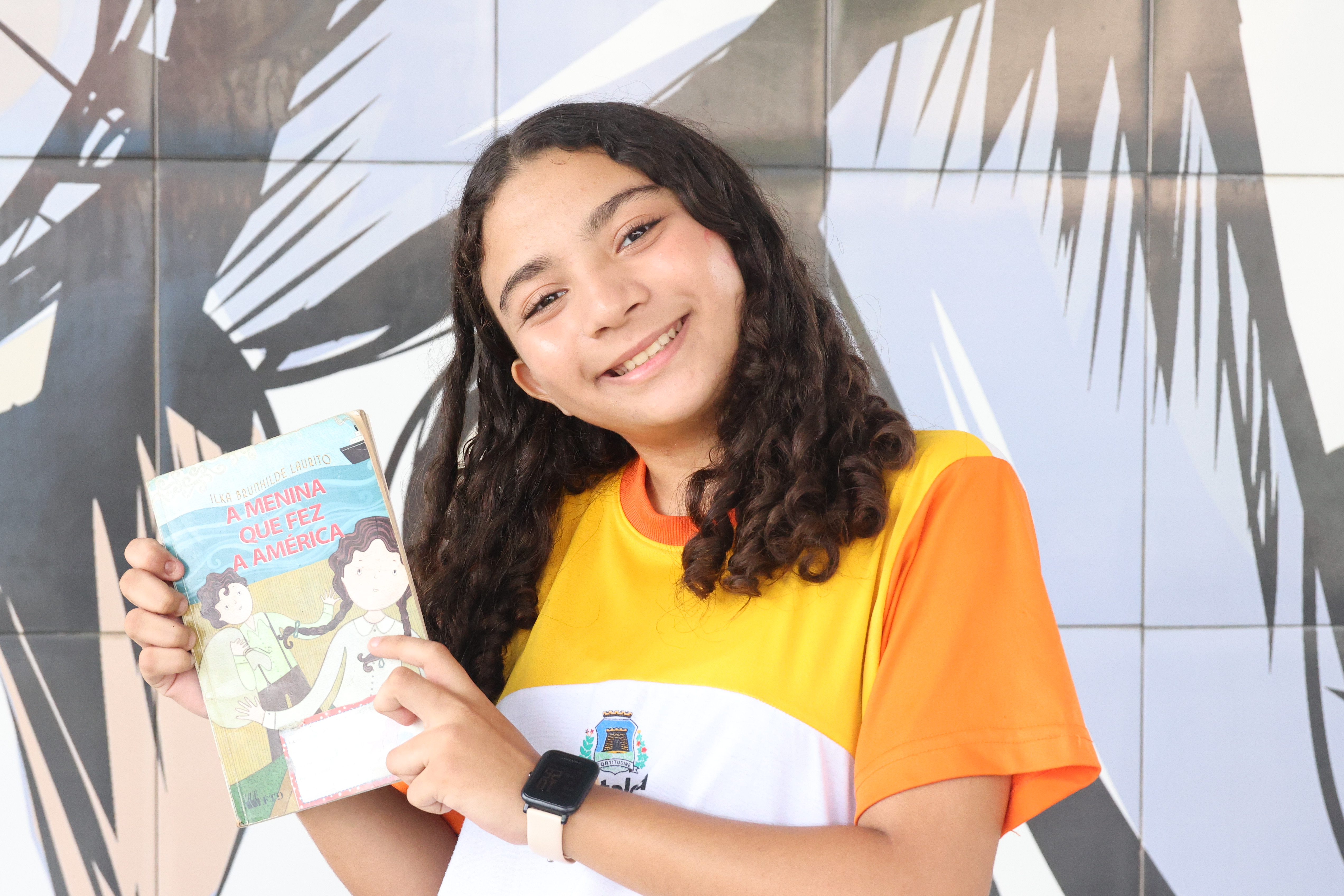 Sofia Paula segurando o livro A menina que fez a América